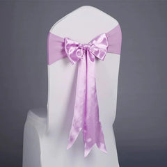 A light purple satin ribbon tied in a bow around the back of a white chair cover.
