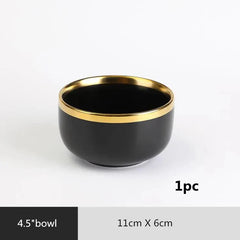 A round black ceramic bowl with a gold-colored rim measuring 11 centimeters by 6 centimeters.