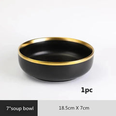 A round black ceramic soup bowl with a gold-colored rim.