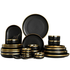 A set of black ceramic dinnerware featuring round plates, bowls, and spoons with gold rims.