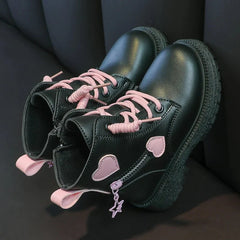 A pair of black ankle boots for girls featuring pink heart accents, pink laces, and side zippers.