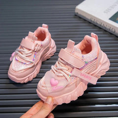 A pair of pink girls' sneakers with glitter accents, hook-and-loop straps, and heart charms.