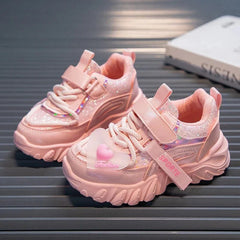 A pair of pink girls' sneakers with glitter accents, hook-and-loop straps, and heart charms.