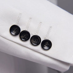 A close-up of a white suit sleeve cuff featuring four black buttons with decorative stitching.
