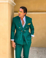 A man wears a slim fit green double-breasted suit with a shawl lapel and a matching belt.