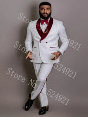 A man wears a white patterned two-piece tuxedo with a burgundy shawl lapel and matching bow tie.