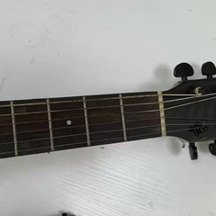 A black guitar chord trainer device attached to the neck of an acoustic guitar.