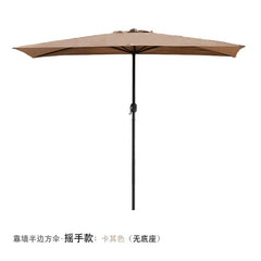 A tan half-shaped outdoor patio umbrella with a hand-crank mechanism and a black pole.