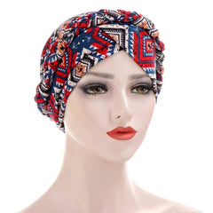 A mannequin head wears a patterned cotton turban with a braided design in red, blue, and white.