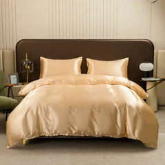 A solid gold satin duvet cover set with two matching pillowcases on a bed.