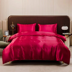 A solid deep red satin duvet cover set with two matching pillowcases on a bed.