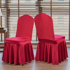 Two red satin chair covers with arched backs and pleated skirts displayed on a wooden floor.