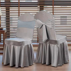 Two silver satin chair covers with pleated skirts, one featuring a decorative back bow.