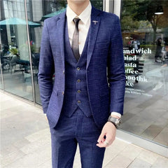 A man wearing a slim-fit navy blue three-piece suit with a subtle grid pattern.