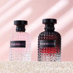Two glass perfume bottles with textured surfaces and black caps stand on a textured surface.