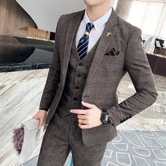 A man wears a brown plaid three-piece suit with a white shirt, blue tie, and pocket square.