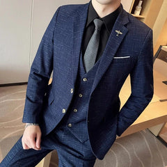 A man wearing a navy blue textured three-piece suit with a black shirt and grey tie.