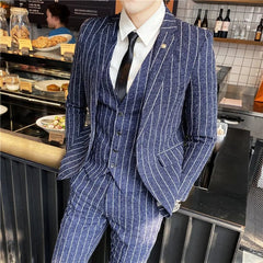 A man wears a navy blue pinstriped three-piece suit with a white shirt and black tie.