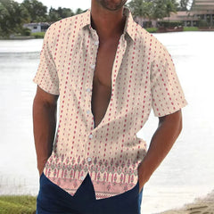 A man wears a short-sleeved, button-down shirt with a beige base, vertical dotted patterns, and a decorative floral border at the hem.