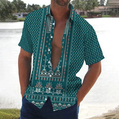 A man wears a teal short-sleeved button-down shirt featuring a white geometric and floral print.