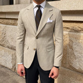 A slim-fitting beige striped blazer with a two-button closure and notched lapels.