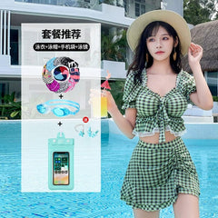 A woman wears a green plaid two-piece swimsuit with a skirt and a square collar top.