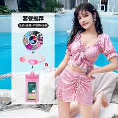 A woman wears a pink and white checkered two-piece swimsuit with a skirt and ruffled top.