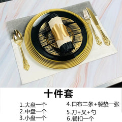 A luxury black and gold dinnerware set featuring plates, cutlery, a napkin, and a placemat.