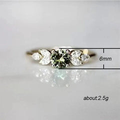 A gold-colored ring featuring a round olive green zircon center stone flanked by leaf-shaped gems.
