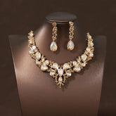 A luxury crystal necklace and earring set featuring teardrop stones on a gold-tone metal base.