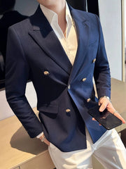 A man wears a navy blue double-breasted slim fit blazer with gold buttons over a white shirt.