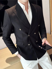 A man wears a black double-breasted slim fit blazer with a white shirt and white trousers.