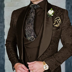 A man wears a brown jacquard three-piece suit with a paisley tie and a white floral boutonniere.