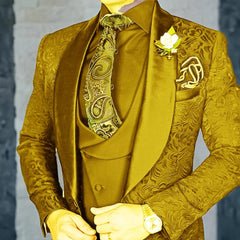 A man wears a gold three-piece jacquard suit with a paisley tie and a white lapel flower.