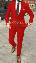 A man wears a bright red two-piece suit with a white shirt and a patterned tie.