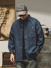 A man wears a loose-fit, long-sleeve navy blue shirt with vertical white stripes.