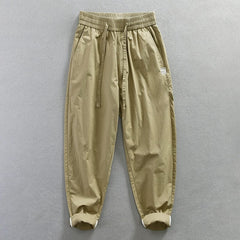 Khaki loose-fit cotton trousers with an elastic waistband and rolled cuffs.