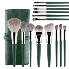 A set of fourteen green makeup brushes with soft bristles and a matching storage case.