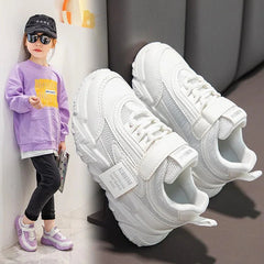 A child wearing white breathable mesh sneakers with hook and loop closures.