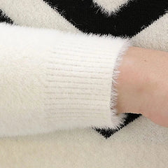 A close-up of a white plush knitted sweater sleeve with a ribbed cuff.