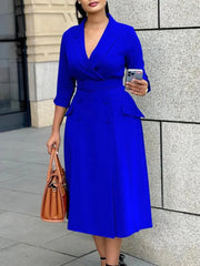 A woman wears a royal blue midi-length office dress with a V-neck, three-quarter sleeves, and belt.