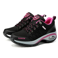 A pair of black and pink lace-up platform sneakers with a visible air cushion in the heel.
