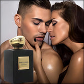 A black perfume bottle labeled Joybelle Prive Ambra Soie stands before a couple in an embrace.