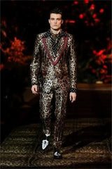A man wears a leopard print velvet suit featuring a maroon lapel and a polka dot shirt.