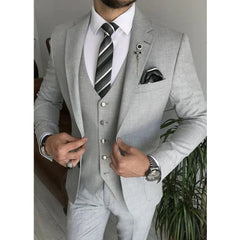 A man wears a light gray three-piece suit with a white shirt and a striped tie.
