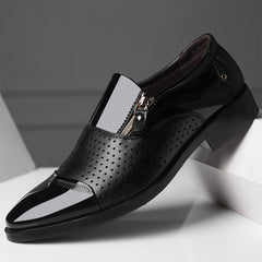 A black pointed-toe dress shoe with a side zipper and perforated leather detailing.