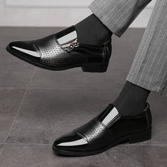 A pair of black pointed-toe dress loafers featuring a side zipper and perforated detailing.