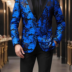 A man wears a blue and black paisley patterned blazer with a single button and lapel collar.