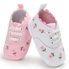 A pair of baby girl canvas crib sneakers featuring a floral print in pink and white.