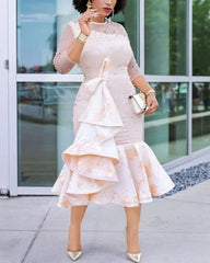 A woman wears an apricot midi dress with beaded mesh sleeves and a ruffled floral skirt.